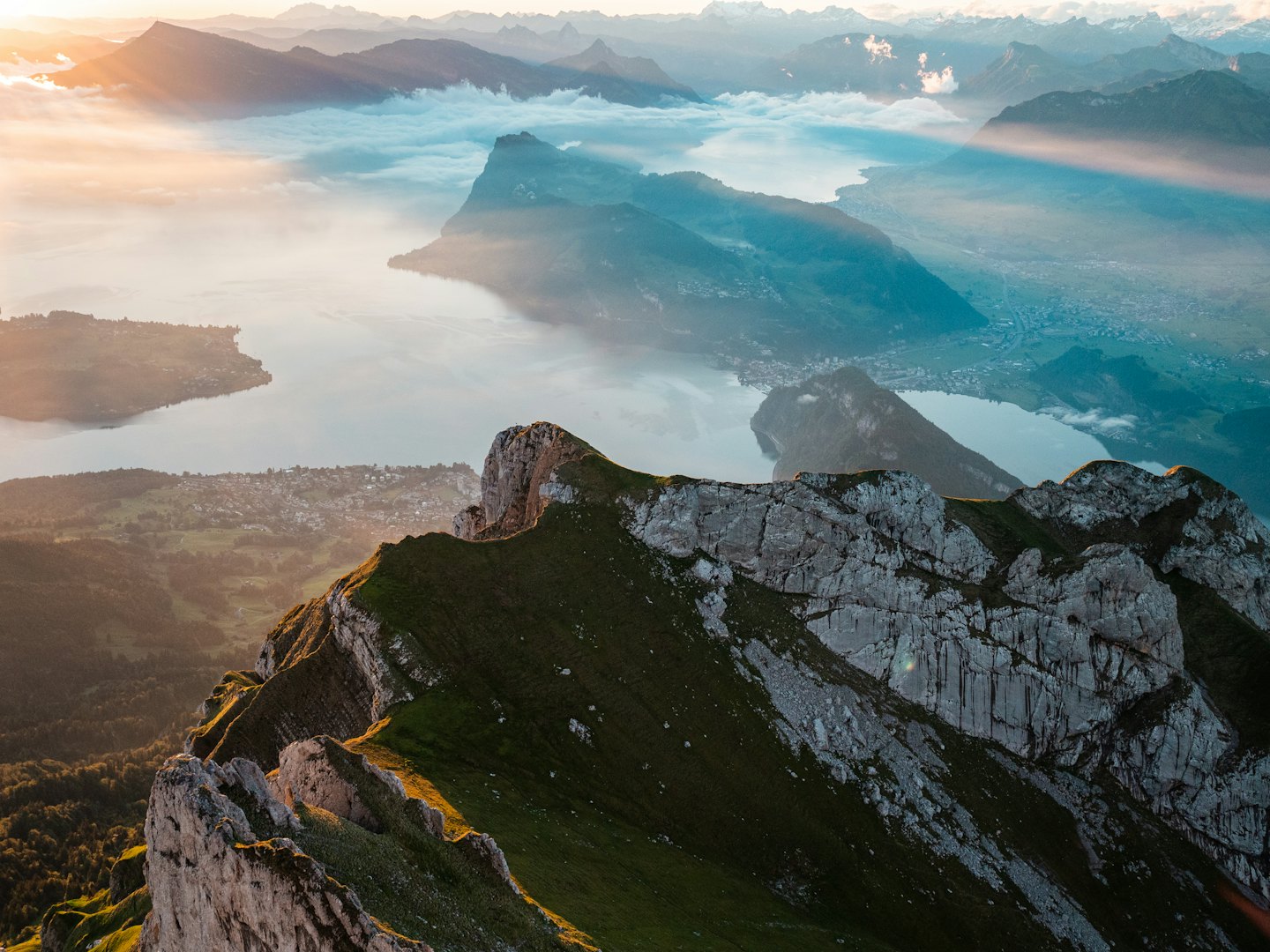 Sunrise over misty mountain peaks and lakes.