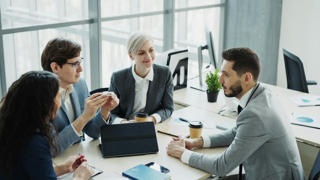 Business professionals in a modern office discussing ideas at a table.